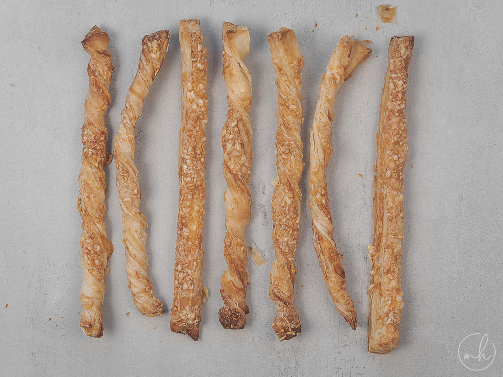 loaded puff pastry cheese straws placed on a grey surface.