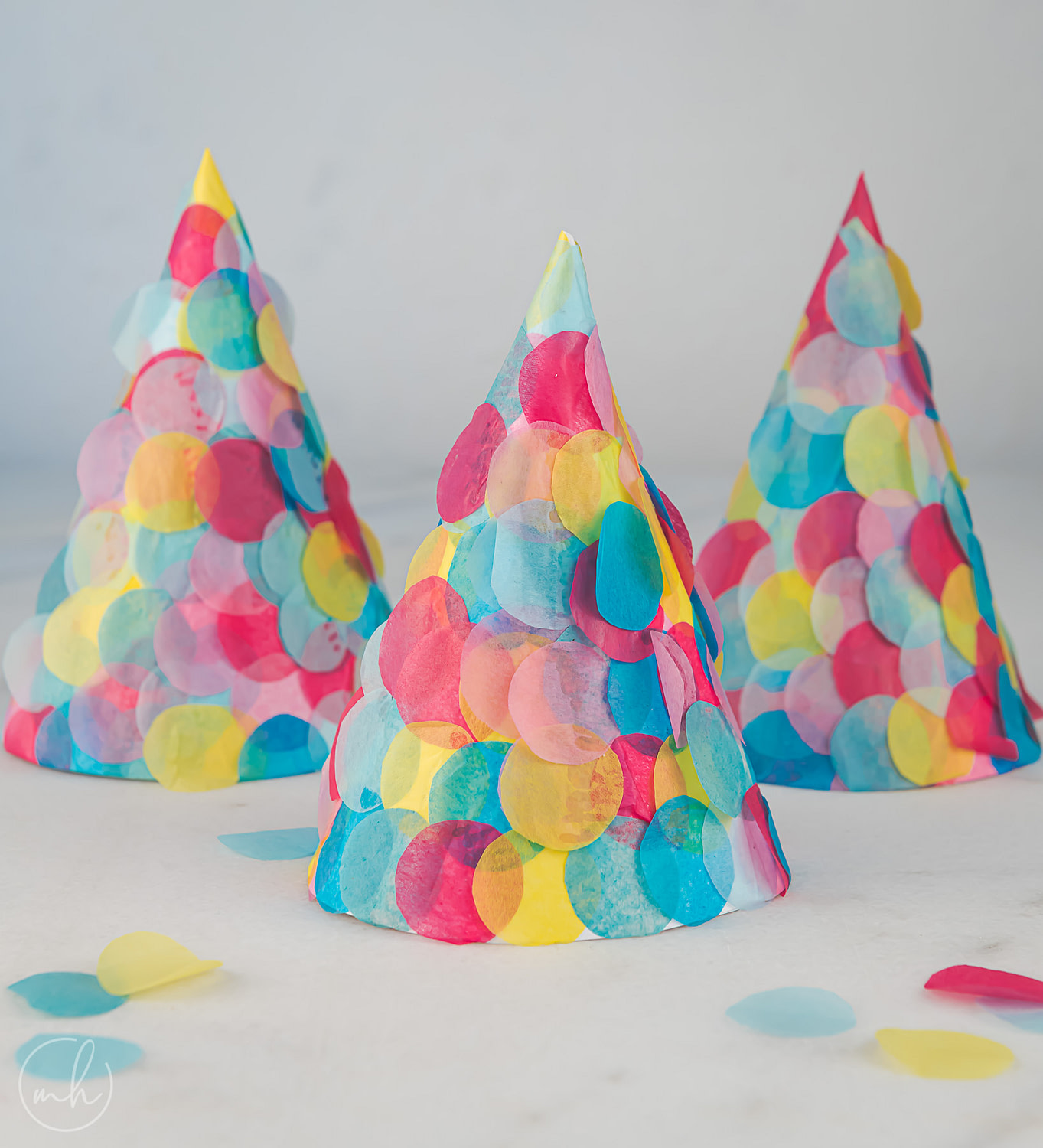 Tissue confetti party hats with scattered confetti.