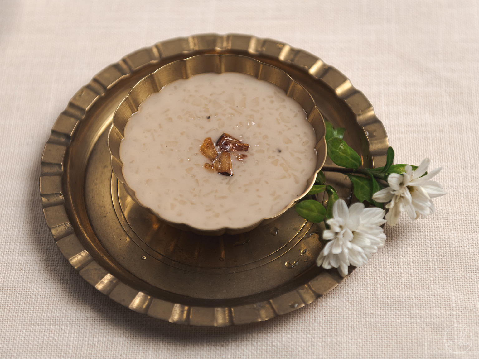 Palada served in a copper bowl, placed on a copper plate with flowers.