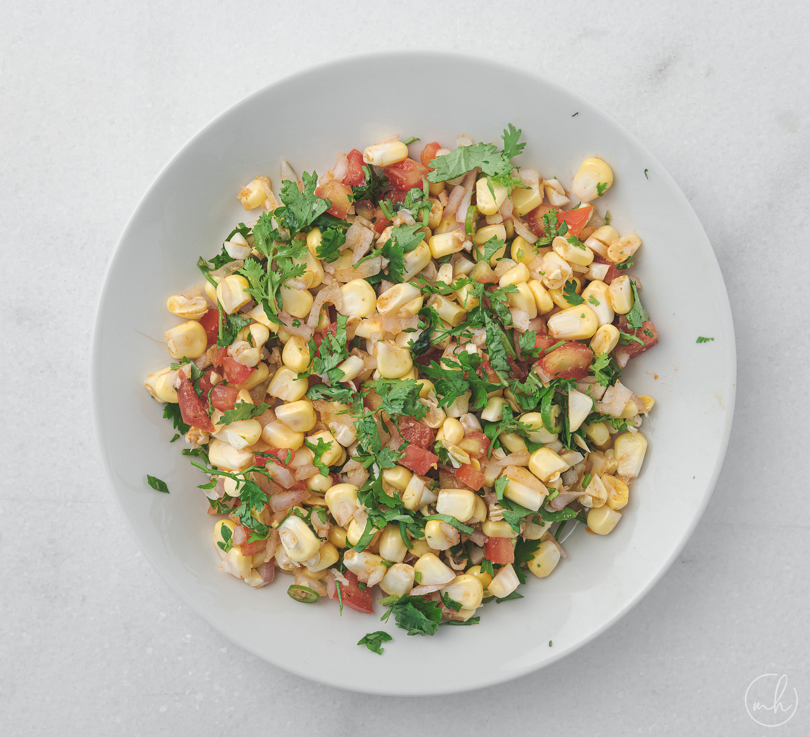 sweet corn salsa chaat placed in a white bowl over a marble surface