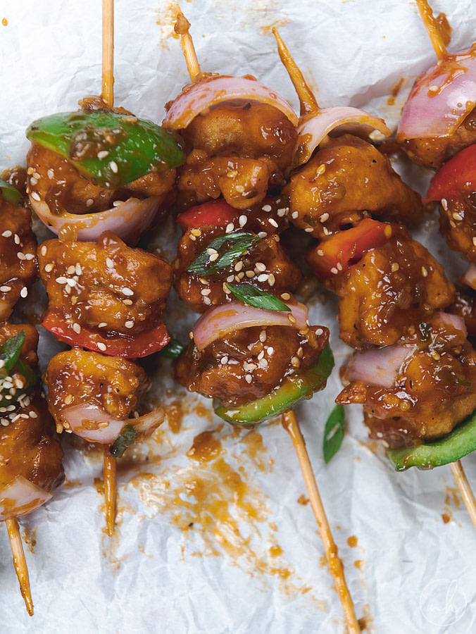 Cauliflower and paneer manchurian skewers, placed on a white parchment paper.