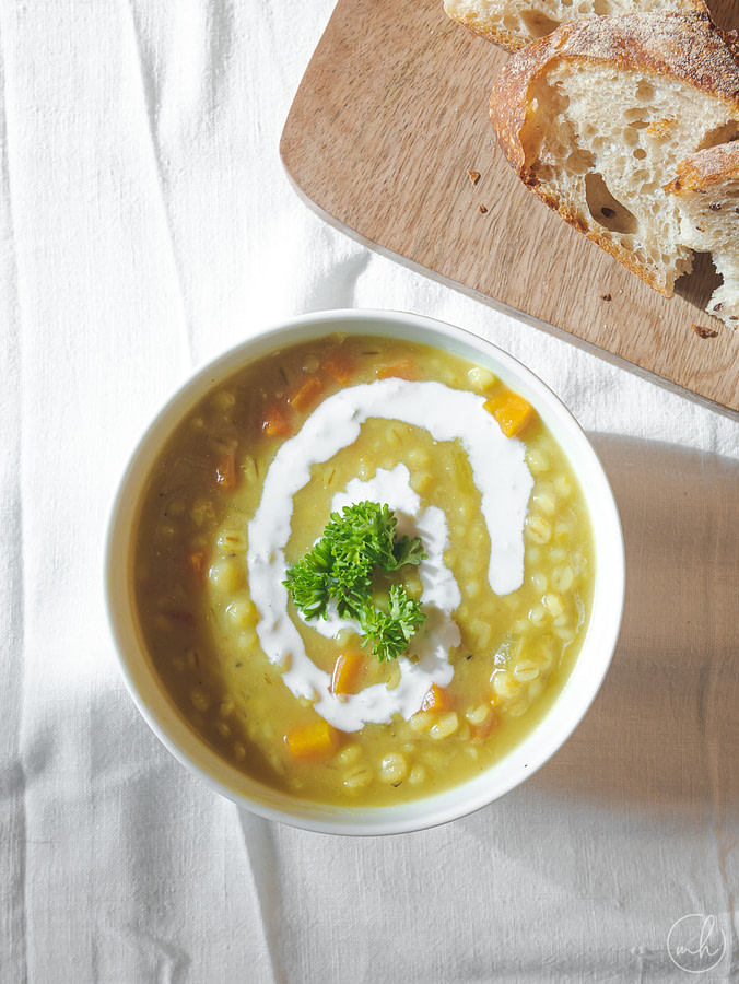 creamy persian pearl barley soup placed on a table with sourdough