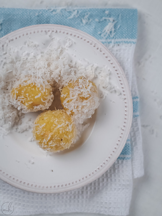 Pineapple coconut energy ball placed on white plate under a blue and white napkin
