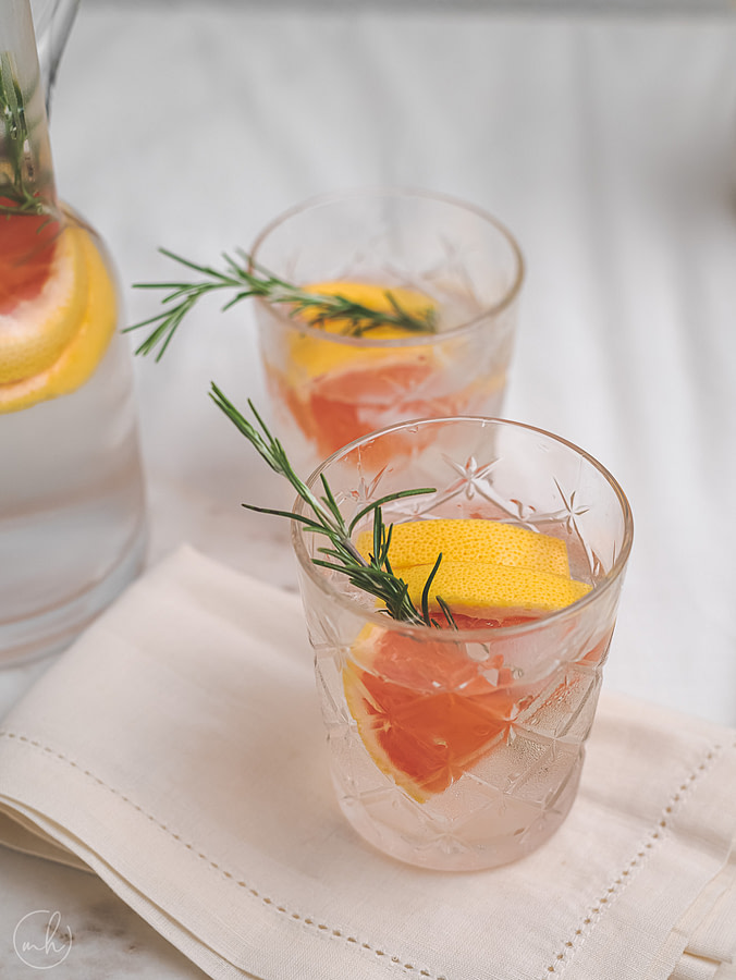 Rosemary grapefruit infused with water poured in two glasses and placed on napkin