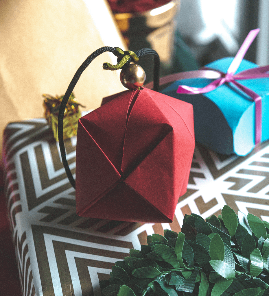 Kagazi: A red colour paper ball on a golden and white striped gift wrapping paper