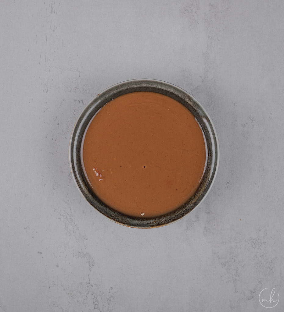 peanut dipping sauce placed in a small bowl over a grey surface